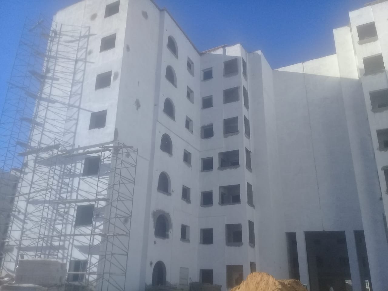 Urban construction site with cranes and buildings in progress under clear sky